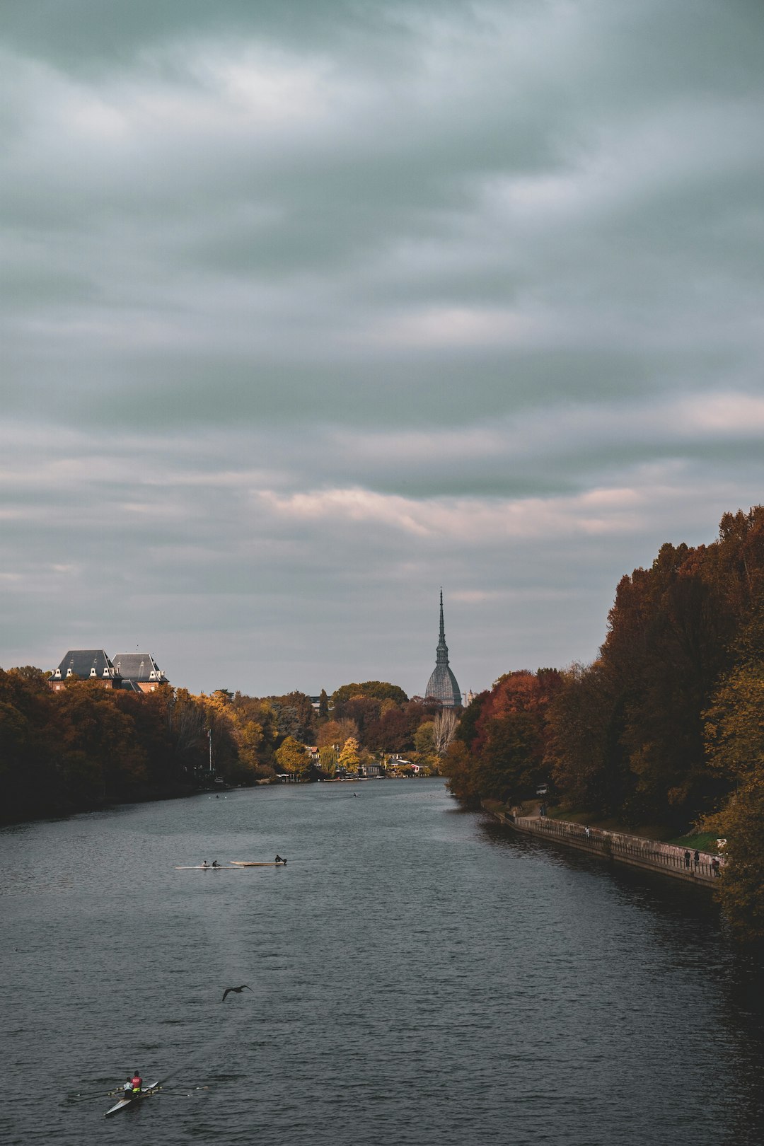 a-body-of-water-surrounded-by-trees-with-a-church-steeple-in-the-background-gjjnbbvbjqw