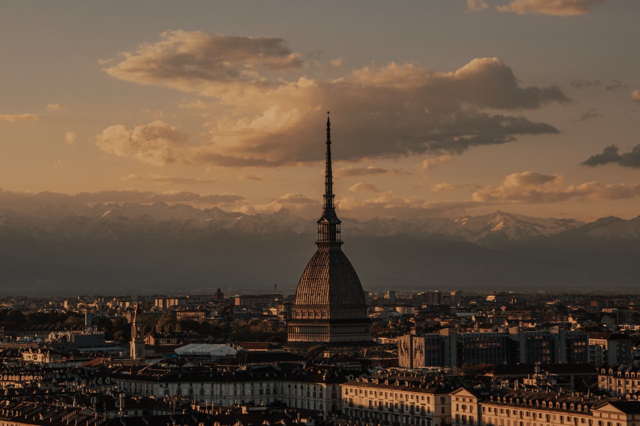 Stunning sunset view of Mole Antonelliana with mountains in the background in Turin, Italy.